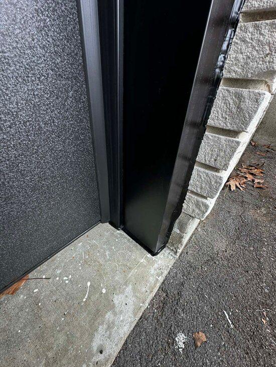 DPS Garage Doors dark aluminum capping finished around a garage door jamb against stone in the GTA