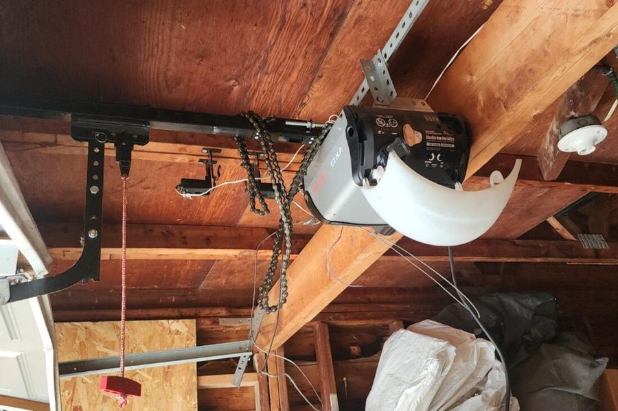 DPS Garage Doors technician servicing a ceiling-mounted chain-drive garage door opener